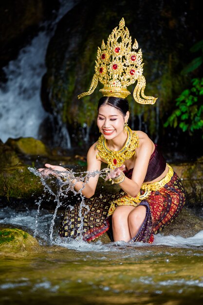 A woman dressed with an ancient Thai dress at the waterfall.