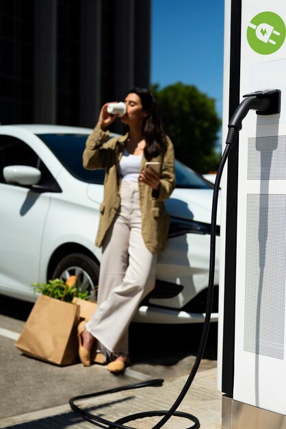 Woman drinking coffee by the car full shot