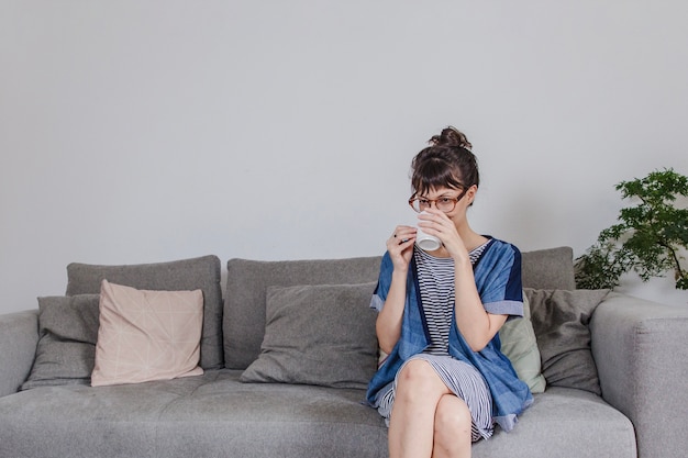 Woman drinking coffee on sofa