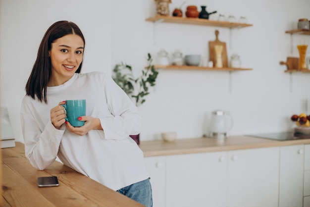 Woman drinking cup of coffee at kitchen at home