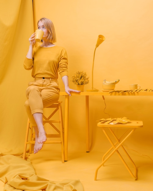 Free photo woman drinking from mug in a yellow scene