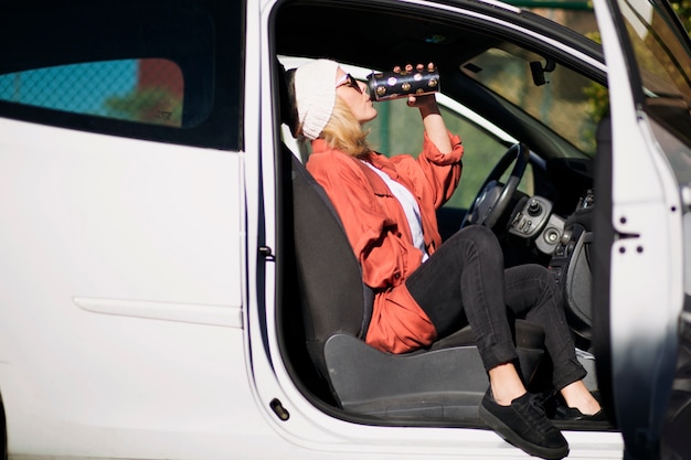 Woman drinking from thermos in car