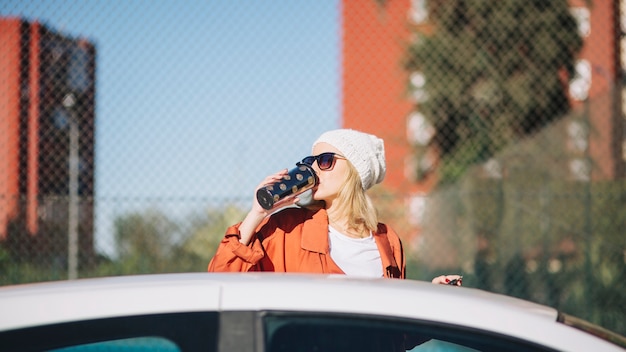 Woman drinking near car