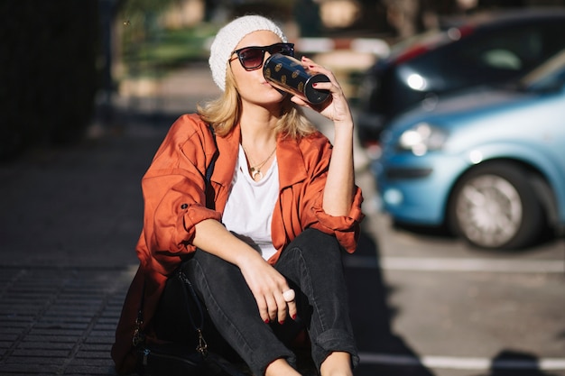 Free photo woman drinking on parking lot