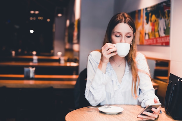 Free photo woman drinking and using smartphone