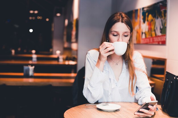 Woman drinking and using smartphone