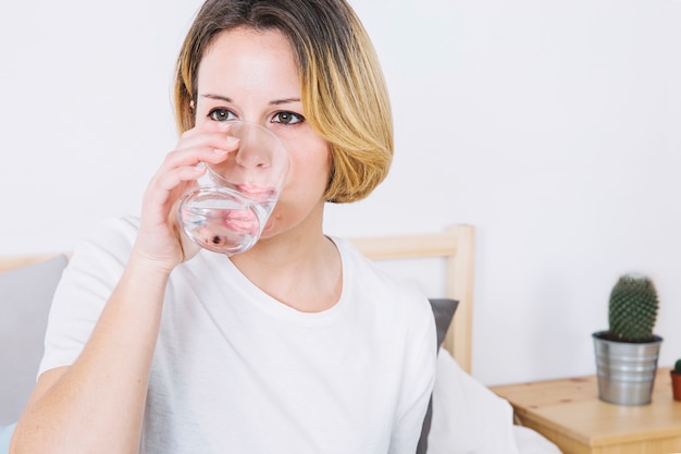 Free photo woman drinking water in bedroom