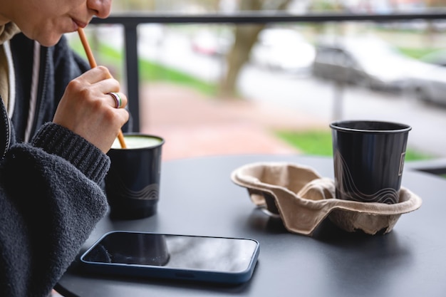 Free Photo a woman drinks coffee on the terrace of a cafe with a smartphone on the table