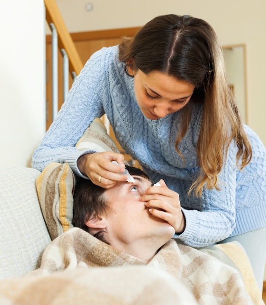 woman  dripping eye drops to man