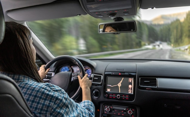 Free photo woman driving a car hands on the wheel closeup view from the back to the road