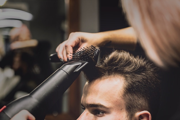 Woman drying and styling hair of man