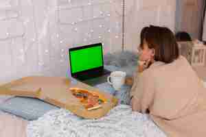 Free photo woman east fast food pizza from delivery on bed in bedroom at home at christmas new year time.