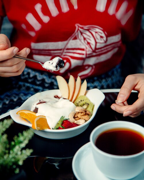 Woman eating chocolate volcano and ice cream mix served with fruit slices and nuts