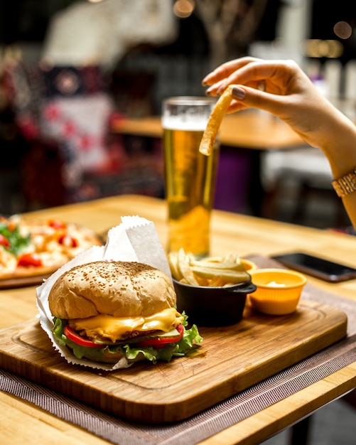 Woman eating french fries and sandwich with cheese and tomato and with sauce