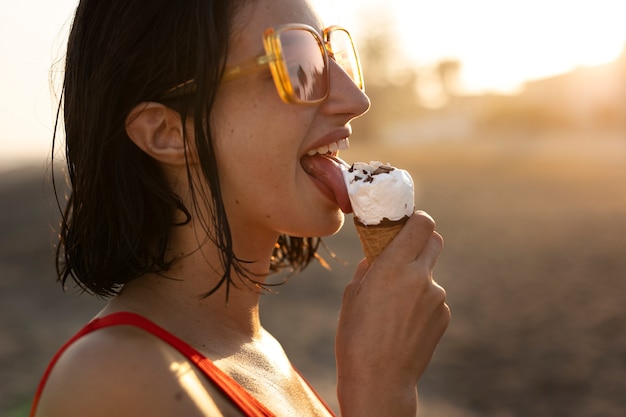 Free Photo woman eating ice cream at seaside side view