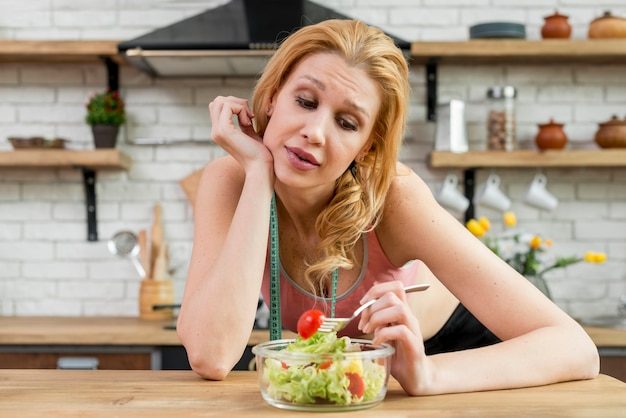 Free photo woman eating a lettuce salad