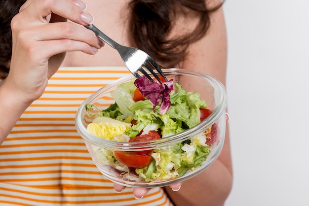 Free photo woman eating a lettuce salad