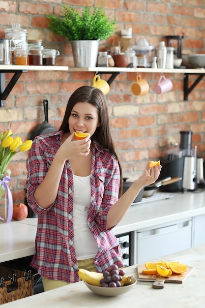 Woman eating oranges in the kitchen