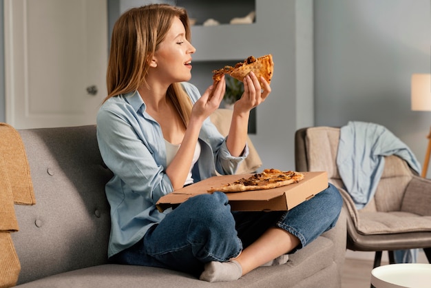 Woman eating pizza while watching tv