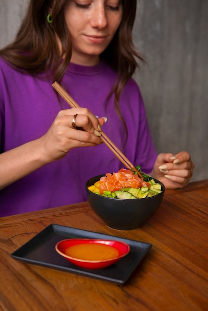 Free photo woman eating salmon dish bowl at the restaurant