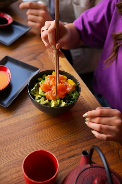 Free Photo woman eating salmon dish bowl at the restaurant