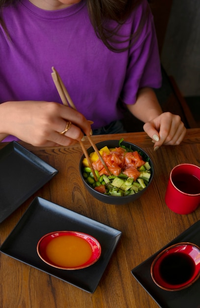 Free Photo woman eating salmon dish bowl at the restaurant