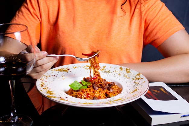 Woman eating spaghetti bolognese with meat pieces