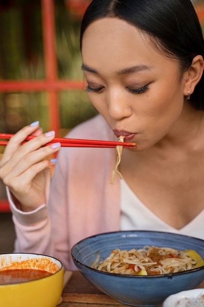 Free photo woman eating with chopsticks front view