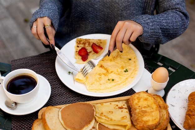 Woman eats omelet and crepe with strawberry