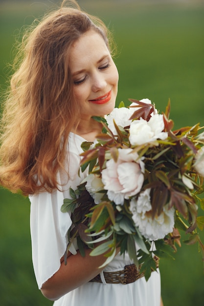 Free photo woman in elegant dress standing in a summer field