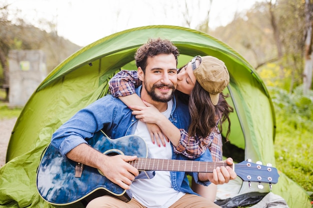 Woman embracing and kissing man with guitar