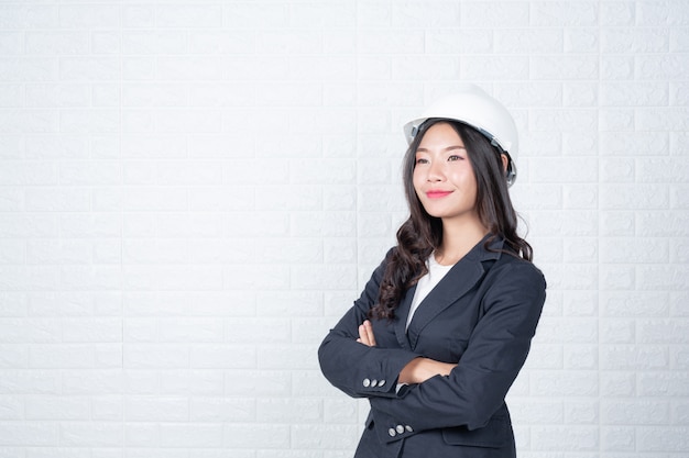 Woman of engineering holding a hat, Separate the white brick wall made gestures with sign language.