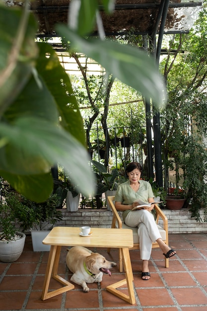 Woman enjoying a book in the garden along with her dog