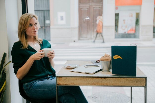 Woman enjoying coffee near cafe window