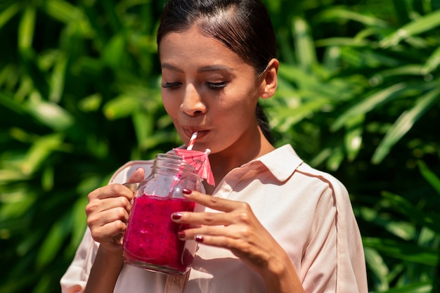 Free photo woman enjoying a dragon fruit drink outdoors