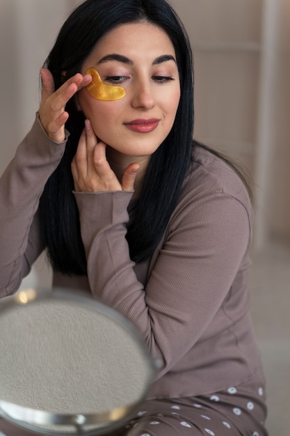 Woman enjoying her beauty routine with golden eye patches