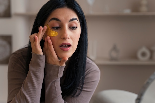 Free photo woman enjoying her beauty routine with golden eye patches