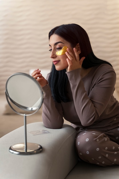 Woman enjoying her beauty routine with golden eye patches