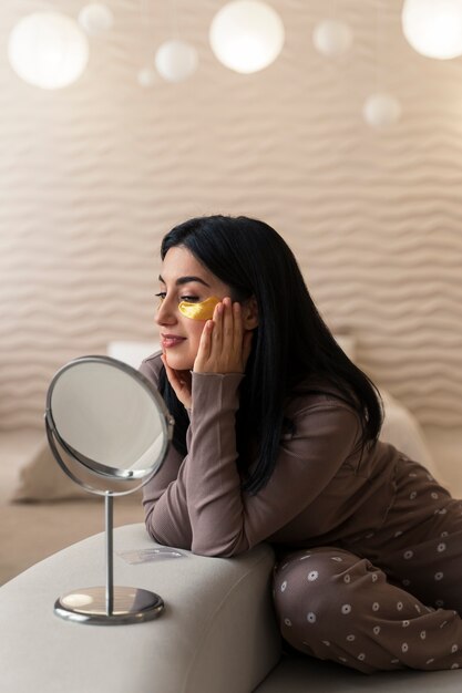 Woman enjoying her beauty routine with golden eye patches