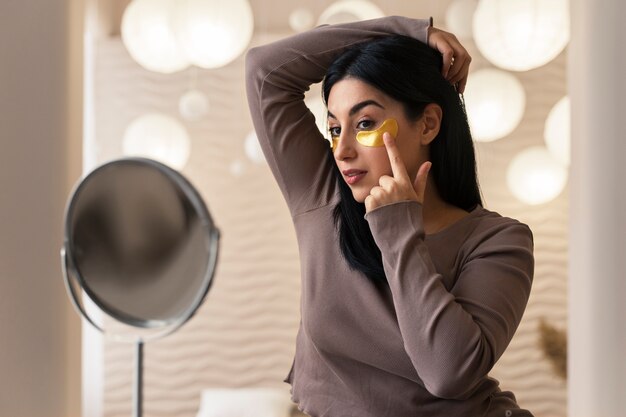 Woman enjoying her beauty routine with golden eye patches