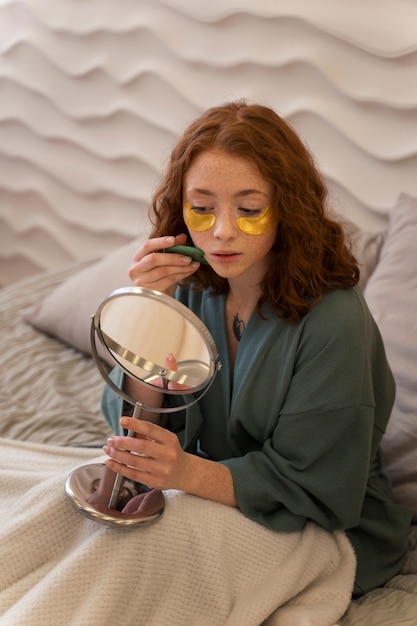 Woman enjoying her beauty routine with golden eye patches