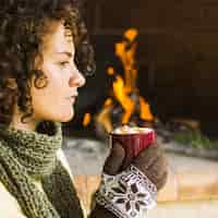 Free photo woman enjoying hot beverage near fireplace