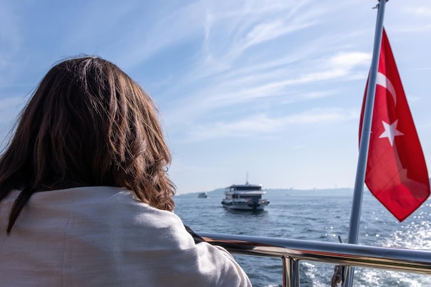 Free photo woman enjoying the view of the boat floating on the black sea near the red flag of turkey