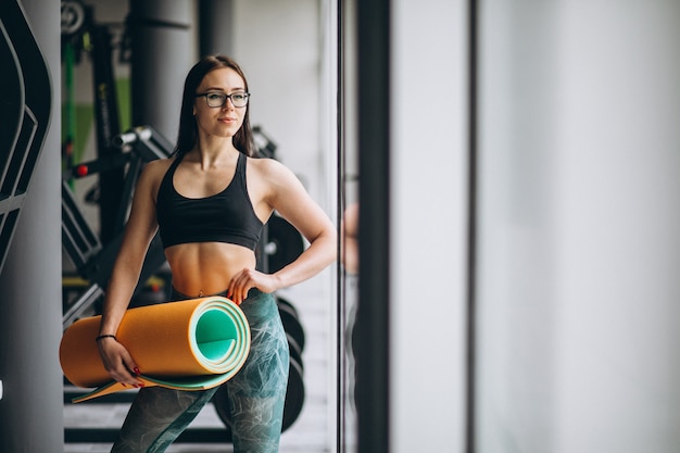 Free photo woman exercing at the gym holding yoga mat