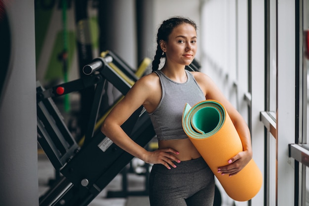 Free photo woman exercing at the gym holding yoga mat