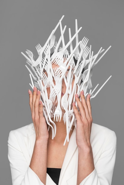 Free photo woman face being covered in plastic tableware