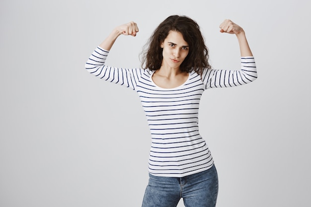 Woman feeling empowered flexing biceps after workout