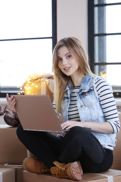 Woman finished with cargo packages and is calling a courrier for shipping via computer