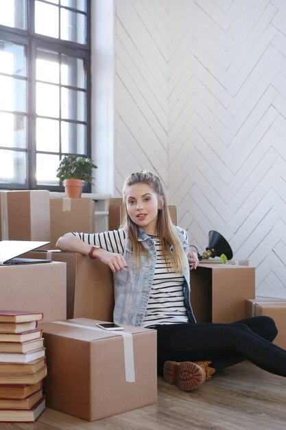 Woman finished with cargo packages and is sitting on the floor in a satisfied manner