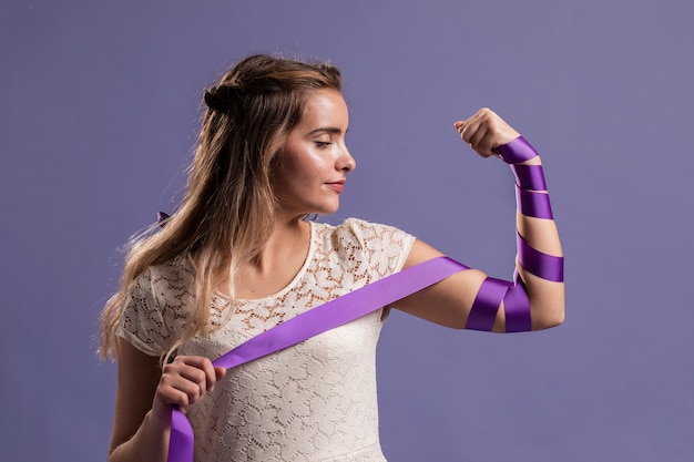 Woman flexing her arm with ribbon as a sign of empowerment